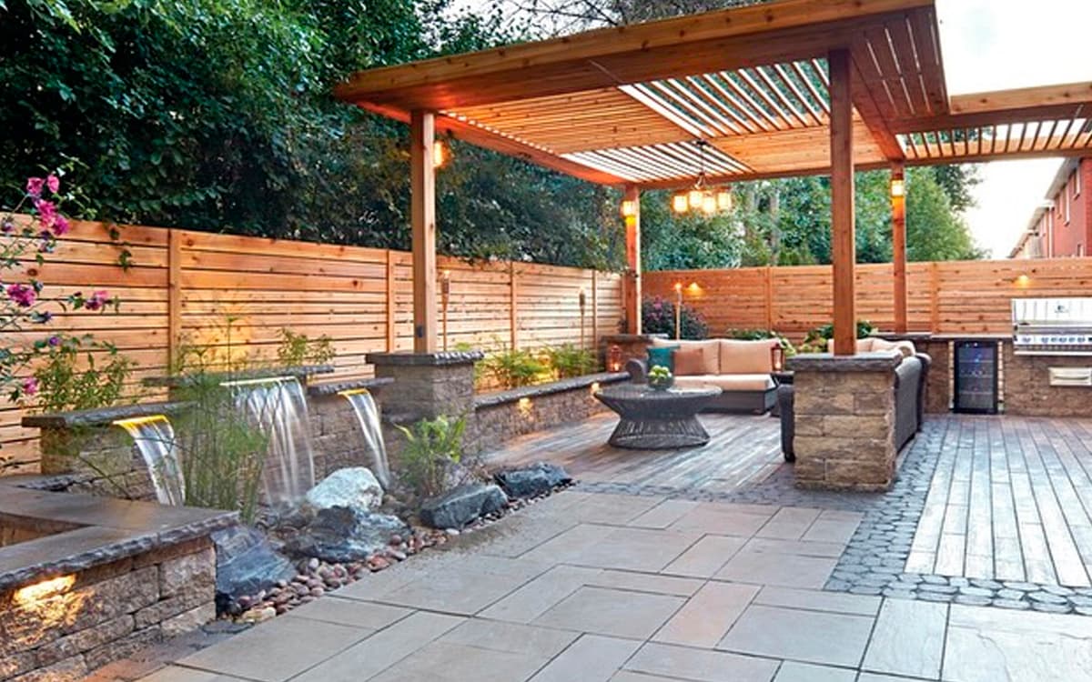 Backyard patio with pergola, stone water features, and seating area created by Expert Hardscaping in Fort Worth, TX
