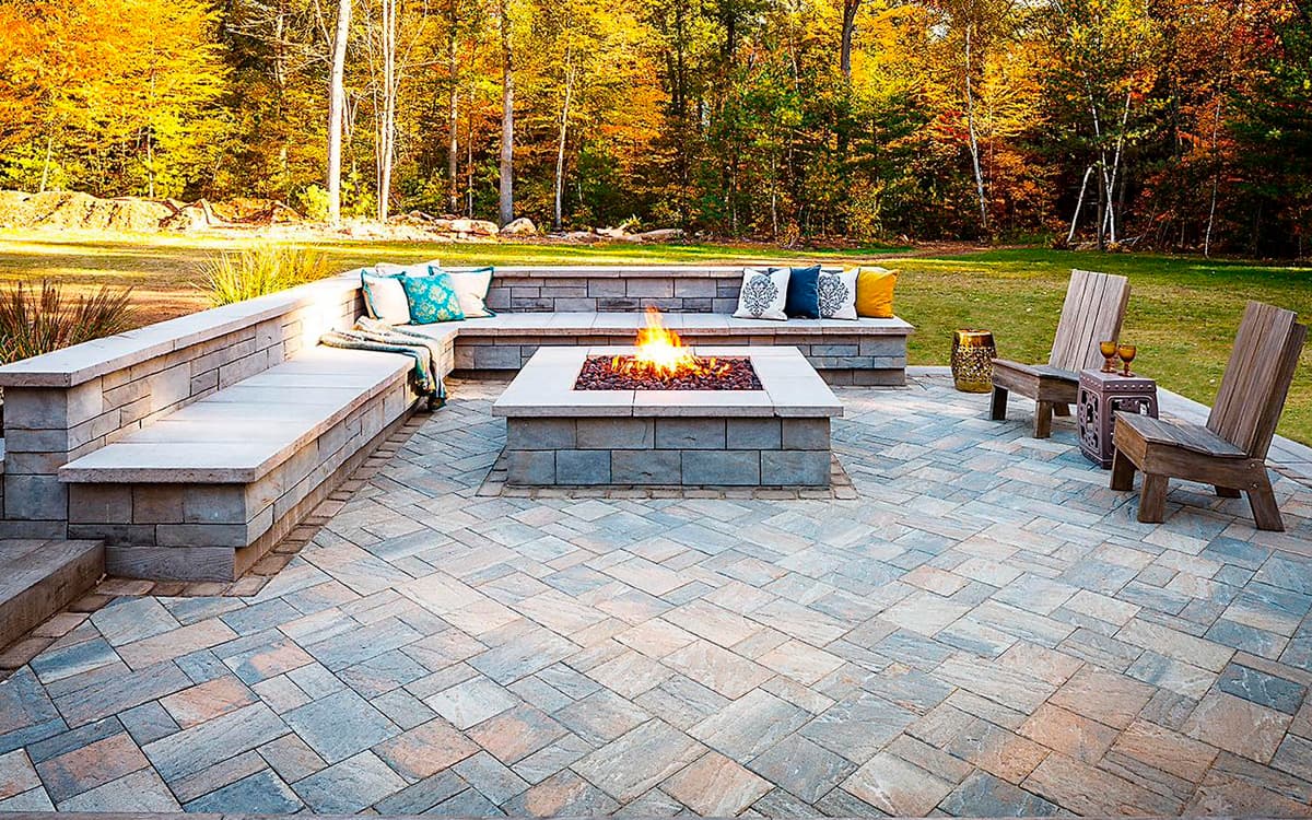 Outdoor patio with stone seating wall, fire pit, and paver flooring built by Expert Hardscaping in Fort Worth, TX