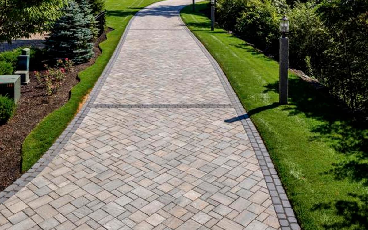 elegant stone driveway with patterned pavers and manicured landscaping built by Expert Hardscaping in Fort Worth, TX